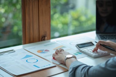 Marketing, Finance, Accounting, Planning, Businesswomen use calculators, computers, and graphs to analyze work to make the company profitable.