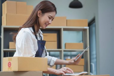 Young businesswoman using a tablet to check online product sales