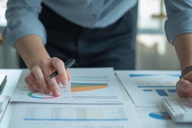 Müşteriler için grafikler kullanarak dengeyi hesaplamak için hesap makinesi ve laptop kullanan bir kadın muhasebecinin portresi.