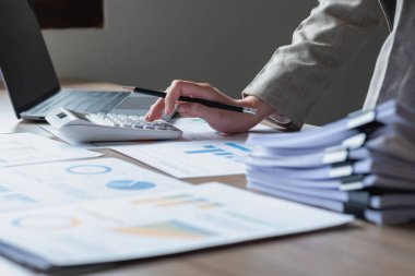 Marketing, Financial, Accounting, Planning, business women analyze company results and profits with graph statistics. Use a laptop computer and a calculator to calculate the company's balance.