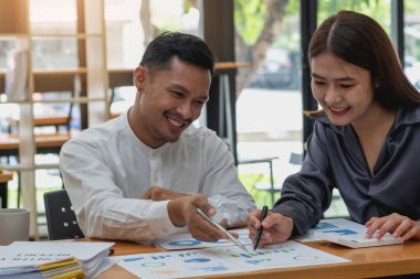 Şirketin pazarlamacı ekibi dizüstü bilgisayar grafikleri ve hesap makineleri kullanarak şirketin kârını analiz ediyor..