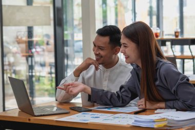 Şirketin pazarlamacı ekibi dizüstü bilgisayar grafikleri ve hesap makineleri kullanarak şirketin kârını analiz ediyor..