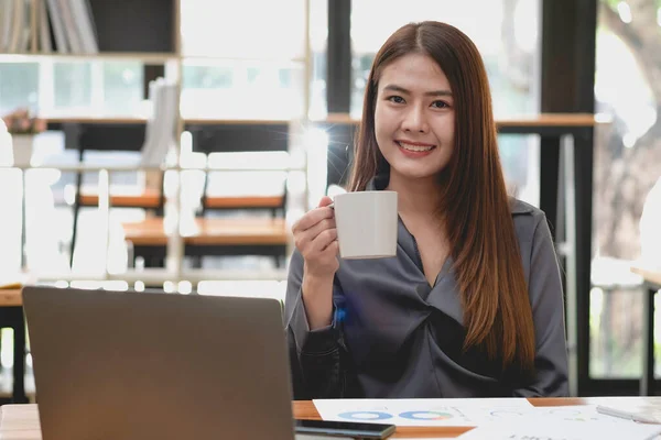 HR workers sit back and relax with coffee on their desks with their computers and documents laying around.