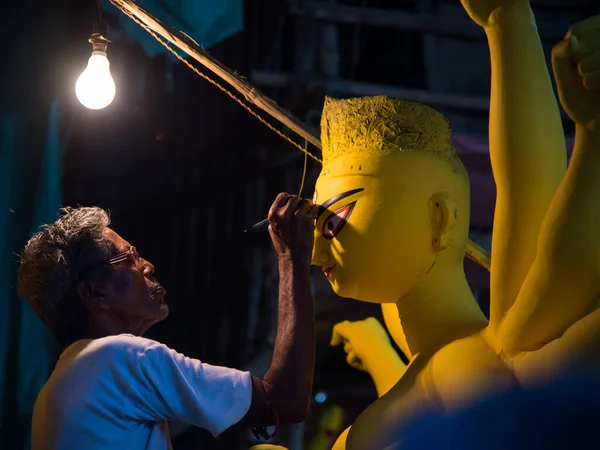 Seçici bir odak ile Durga putunu çizen bir adam 