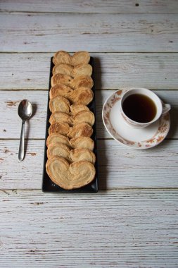 Fırın bisküvilerinden taze taze siyah bir tepside seçici odaklı siyah çay ile servis edilir. Üst görünüm.