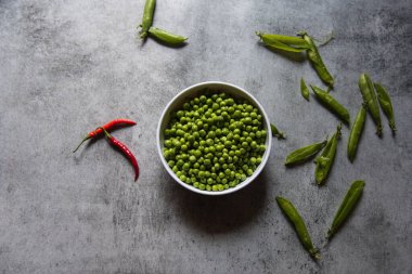 Raw green peas in a white bowl on a background. View from above.