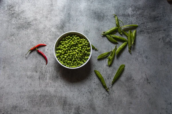 Raw green peas in a white bowl on a background. View from above.