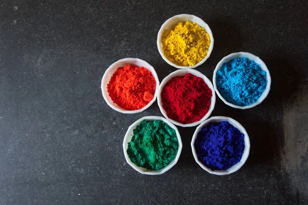 Seçici odak kullanımı ile koyu bir arkaplan üzerinde kase içindeki gulal veya holi renkleri