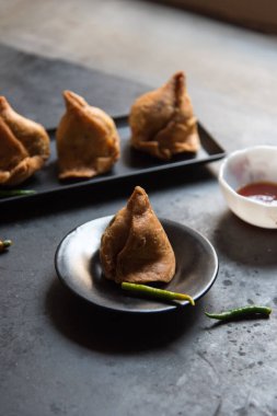 Siyah bir tabakta meşhur Hint atıştırmalığı samosa. Yaklaş, seçici odaklanma. 