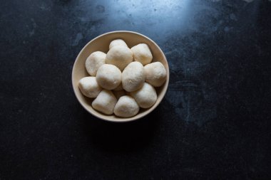 Tatlı bir rasgulla ya da koyu arkaplanda bir kasede kuru rosogolla. Üst görünüm.