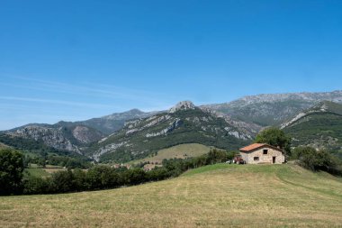 Dağlık bir alanda tarlalar, bir çiftlik evi ve kapısında karavanı olan bir traktör, Arenas de Cabrales, Asturias, İspanya, yatay