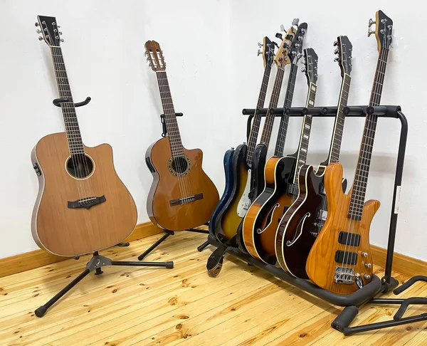 different electric guitars, bass guitars, acoustic and classical guitars on stands in a recording studio or music academy, horizontal