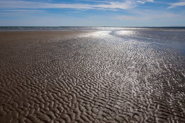 Sahilin kumlarında izler ve oyuklar alçak gelgitte deniz ve arka planda gökyüzü, Isla Canela plajı, Ayamonte, Huelva, İspanya, deniz manzarası