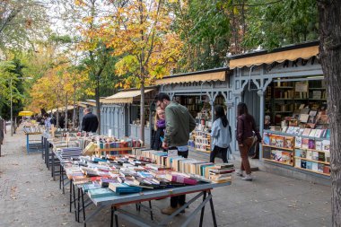 Madrid, İspanya; 25 Kasım 2017: Retiro Park yakınlarındaki sokakta tezgah satmak, yoldan geçenlerden bazıları masalarda sergilenen kitapları karıştırıyor