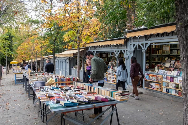 Madrid, İspanya; 25 Kasım 2017: Retiro Park yakınlarındaki sokakta tezgah satmak, yoldan geçenlerden bazıları masalarda sergilenen kitapları karıştırıyor