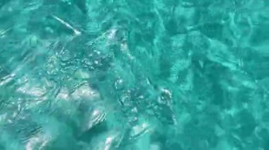 turquoise water texture on a beach with crystal clear water and white sand, light waves with sun reflections on a summer day, turquoise blue water undulations, resolution 4k
