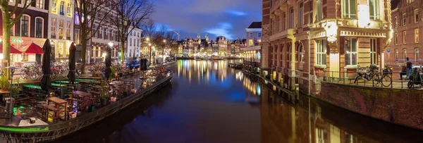 Gyönyörű régi házak a város vízpartján Amszterdam naplementekor. — Stock Fotó