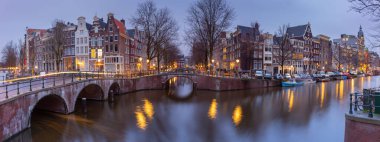 Gün batımında Amsterdam 'ın rıhtımındaki güzel eski evler.