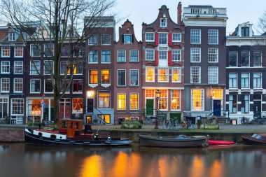 Gün batımında şehrin seddini ve ortaçağ peri evlerinin cephelerini gösteren resimli bir manzara. Amsterdam mı? Hollanda.