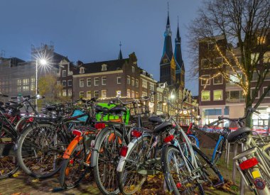 Gün batımında şehrin seddini ve ortaçağ peri evlerinin cephelerini gösteren resimli bir manzara. Amsterdam mı? Hollanda.