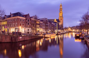 Gün batımında şehrin seddini ve ortaçağ peri evlerinin cephelerini gösteren resimli bir manzara. Amsterdam mı? Hollanda.