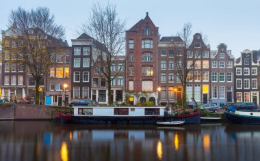 Gün batımında şehrin seddini ve ortaçağ peri evlerinin cephelerini gösteren resimli bir manzara. Amsterdam mı? Hollanda.