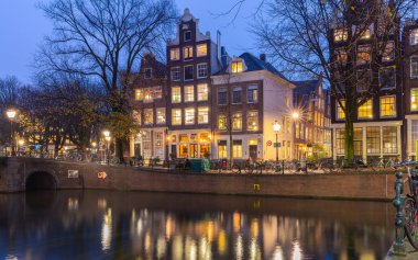 Gün batımında şehrin seddini ve ortaçağ peri evlerinin cephelerini gösteren resimli bir manzara. Amsterdam mı? Hollanda.
