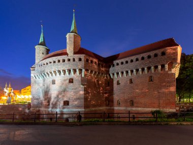 Stone building of the Barbican Fort in Krakow in the night illumination at dawn. Poland.