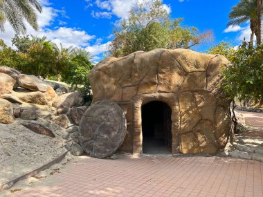 İsa 'nın boş mezarının kopyası zemin döşeme alanı ve arka planda ağaçlarla dolu parlak mavi gökyüzü..