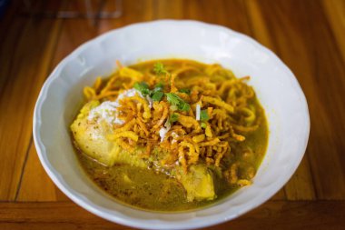 Körili erişte çorbası (Khao Soi Kai), Kuzey Tayland 'da ahşap arka planda bulunan bir yemek türüdür..