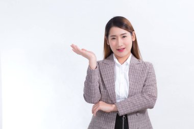 Asyalı çalışan kadın gülümsüyor ve beyaz arka planda bir şey göstermek için ellerini gösteriyor..