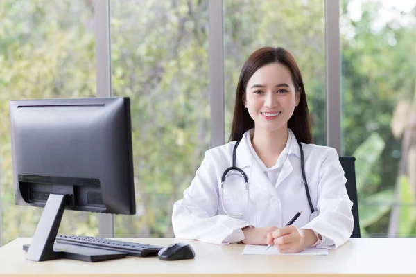 身穿医疗服的亚洲专业女医生在医院的办公室里工作 而电脑则放在桌上 — 图库照片