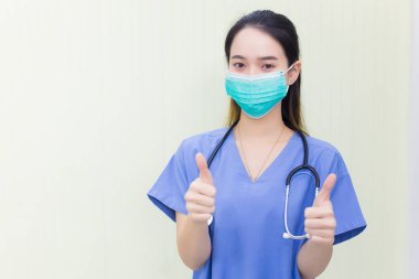 Tıbbi maske takan genç bir Asyalı kadın doktor beyaz bir arka planda el sıkışırken kendini gösteriyor. Solunum sistemini (Covid-19) korumak için maske takıyor..