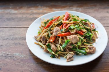 Sarımsak soğanlı domuz eti, Tayland 'ın kuzeyinde geleneksel bir Akhas yemeğidir. Tahta bir masaya beyaz bir tabak koydu..