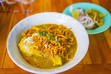 Kuzey Tayland Köri Eriştesi (Khao Soi Kai) Tayland 'ın kuzeyinde bulunan geleneksel bir yemektir. Çorbanın tadı baharatlı ve tatlı. Üstüne çıtır çıtır sarı erişte ekleyip ahşap masaya koyuyor..