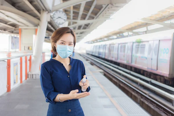 亚洲女人正在车站等火车 她喷酒洗手 并戴上医疗面罩作为医疗保健和新的正常生活方式 — 图库照片