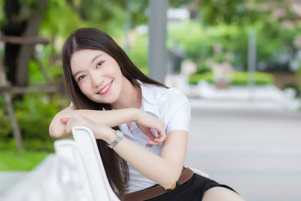 一个穿着大学生制服的泰国成人学生的画像 亚洲漂亮女孩坐在大学里 幸福地微笑着 背负着花园的树木 — 图库照片