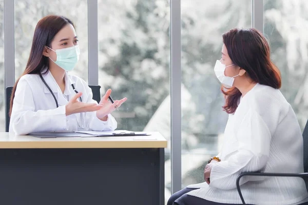 Asian elder female consults with professional doctor about her symptom or health problem in examination room at hospital.