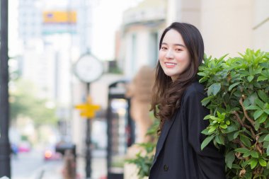 Uzun saçlı, güzel Asyalı bir kadının kışın moda portresi şehirde sokakta dikilirken siyah bir ceket giyer..