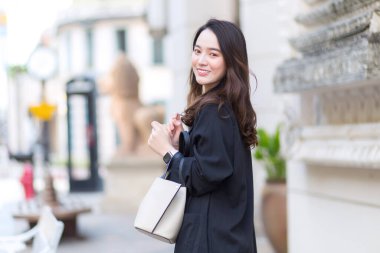 Genç, şık, hippi Asya 'lı bir kadının portresi sokakta yürüyor, şık kıyafetler giyiyor, arkasını dönüyor ve kış güneşli yaşam tarzında düşünceli görünüyor. .