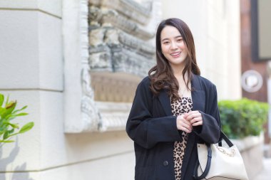 Genç, şık hippi işi portresi güzel Asyalı kadın sokakta yürüyor, şık kıyafetler giyiyor, arkasını dönüyor ve kışın düşünceli görünüyor..