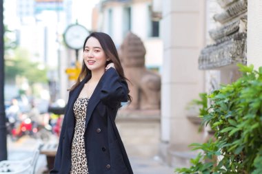 Uzun saçlı, güzel Asyalı bir kadının kışın moda portresi şehirde sokakta yürürken siyah bir ceket giyer..