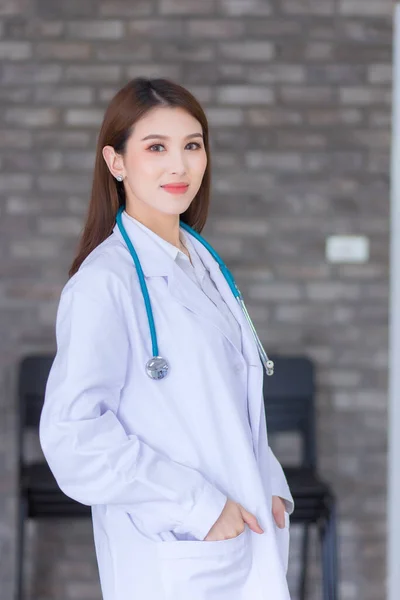 病院で幸せと笑顔をポケットに手で立っているアジアの女性医師 白いローブと聴診器を身に着けてる 新しい標準と医療の概念 — ストック写真