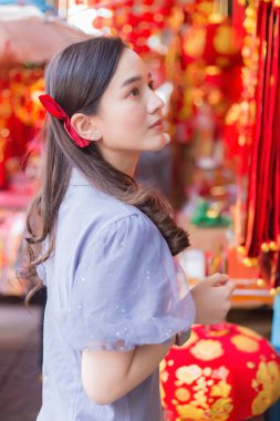 Uzun saçlı Asyalı kadın Çin Yeni Yıl temalı bir şeye bakıyor..