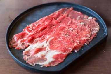 Fresh beef raw sliced was served for Sukiyaki and Shabu or Yakiniku restaurant which it put on black plate.