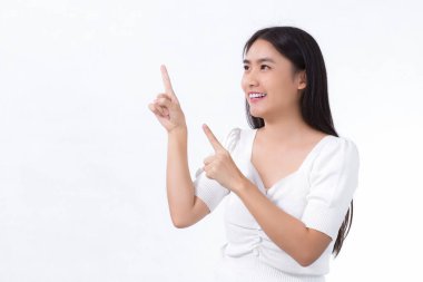 Siyah uzun saçlı Asyalı kadın beyaz gömlek giyiyor ve beyaz arka planda bir şeyler göstermek için işaret ediyor..