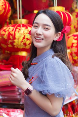 Mavi, gri, Çinli Qipao elbiseli Asyalı kadın Çin dilinde mutlu anlamına gelen ve arka plan olarak beyaz ahşap kapının üzerinde duran bez çantayı tutuyor.