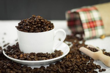 Beyaz bir fincanda kavrulmuş Arap kahve çekirdekleri. Bardak kahve çekirdekleri ile dolu.