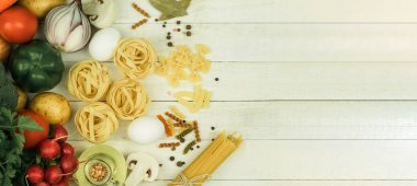 Tahta bir masada çeşitli türde çiğ makarna ve baharatlar. Yukarıdan bak. Tahta masadaki makarna, metin için boşluk