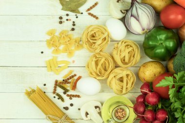Tahta bir masada çeşitli türde çiğ makarna ve baharatlar. Yukarıdan bak. Tahta masadaki makarna, metin için boşluk